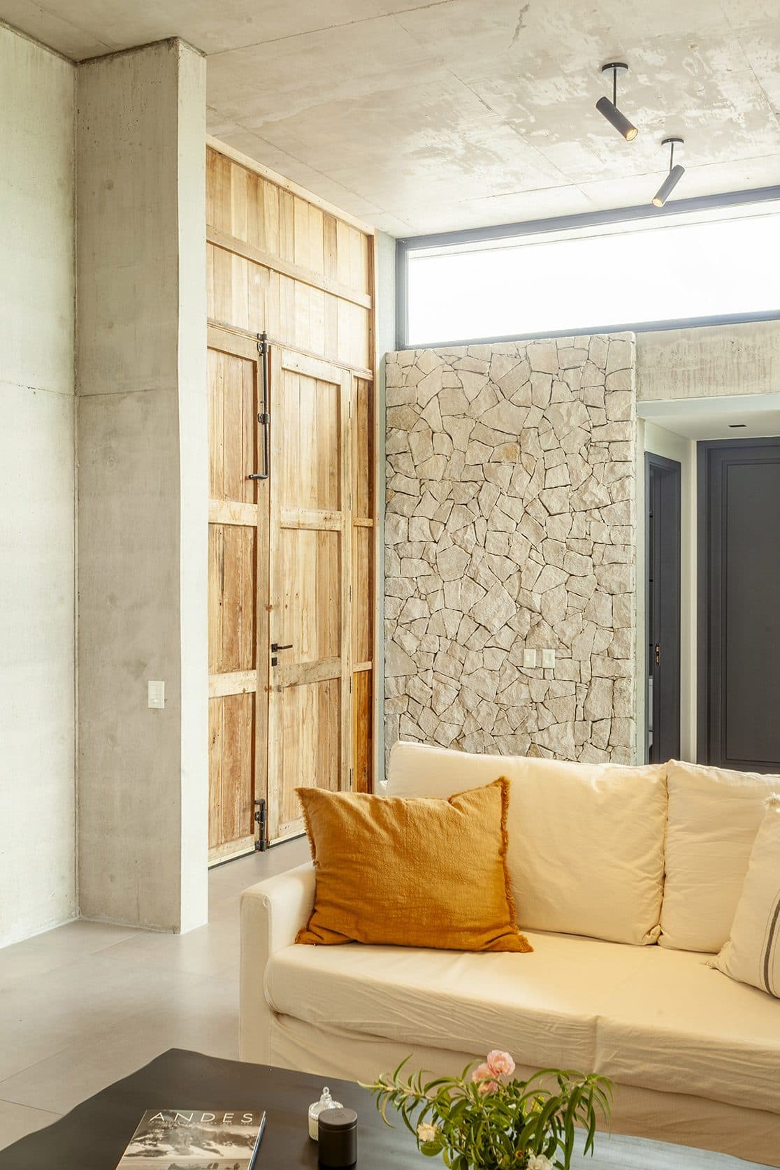 Interior with a stone wall, timber joinery and a light armchair