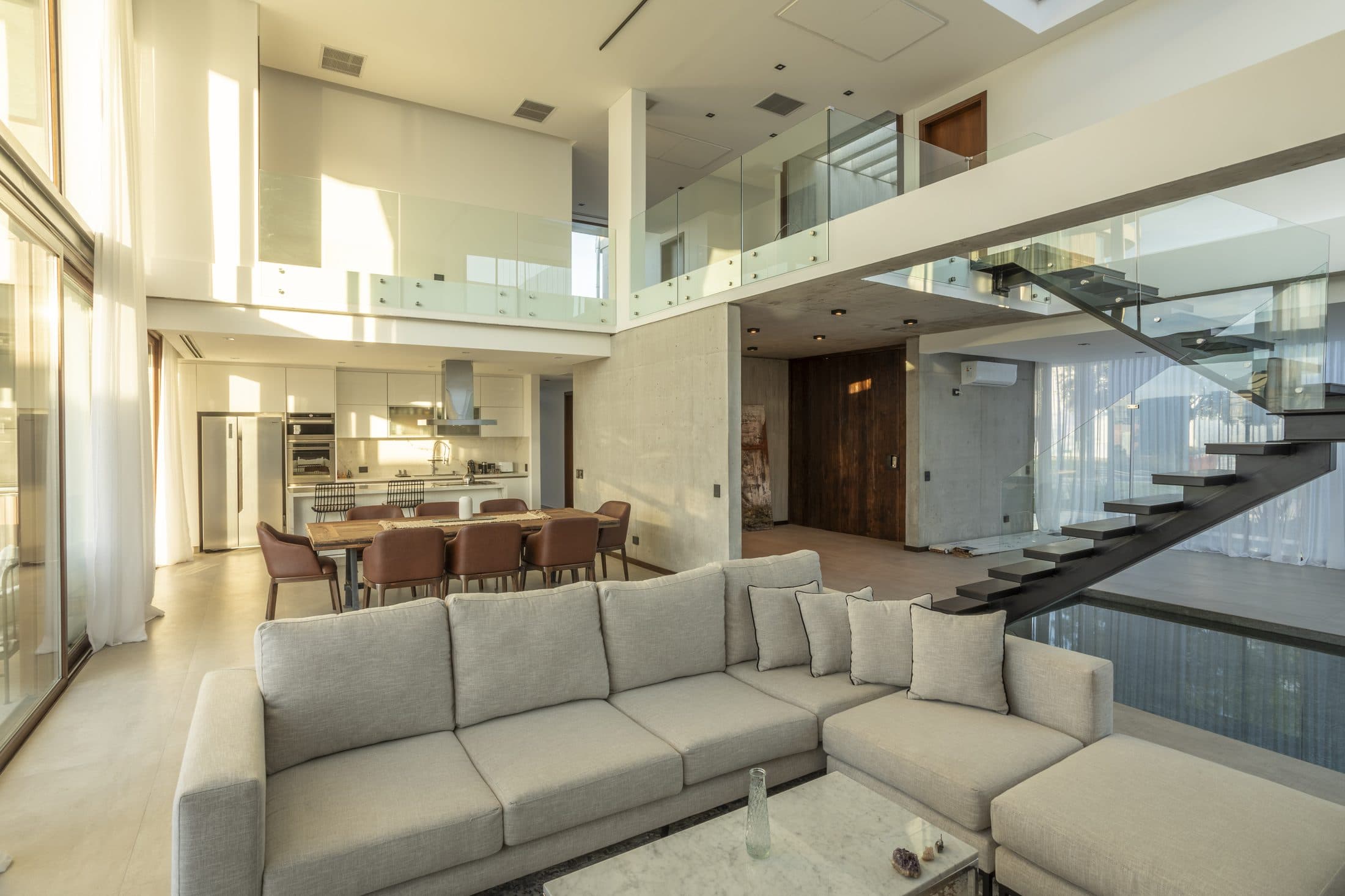 Double-height living room with light filtered by curtains